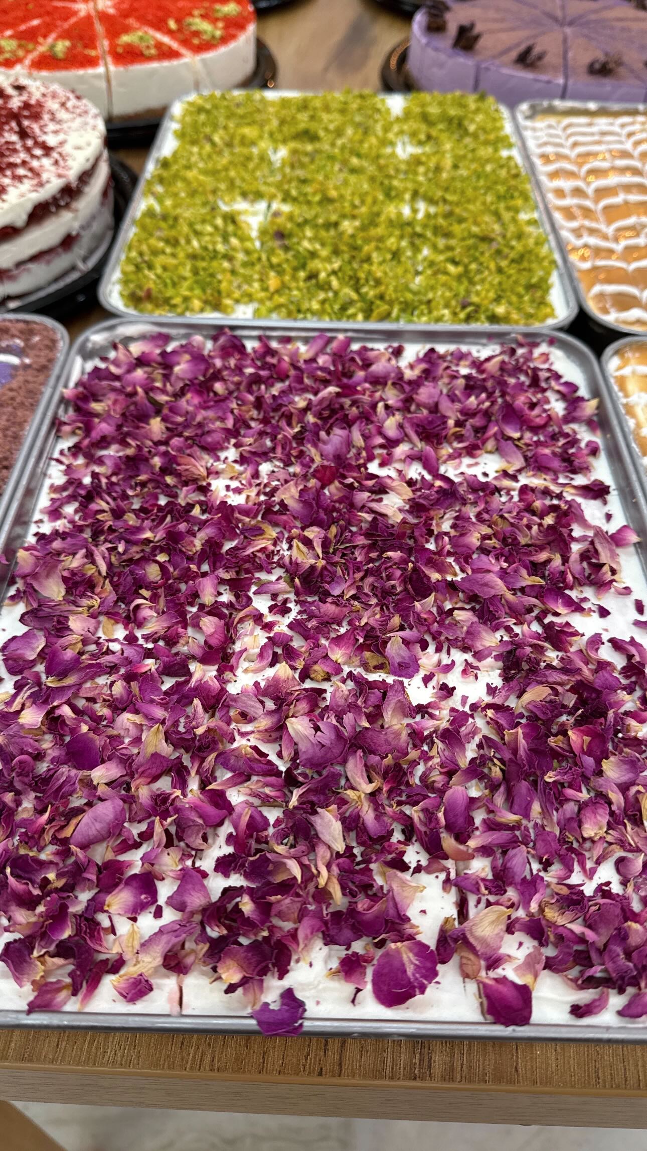 Trays of cheesecake topped with dried rose petals and pistachio